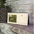 Small flip Calendar on a ledge with a glass frog illustration on the cover