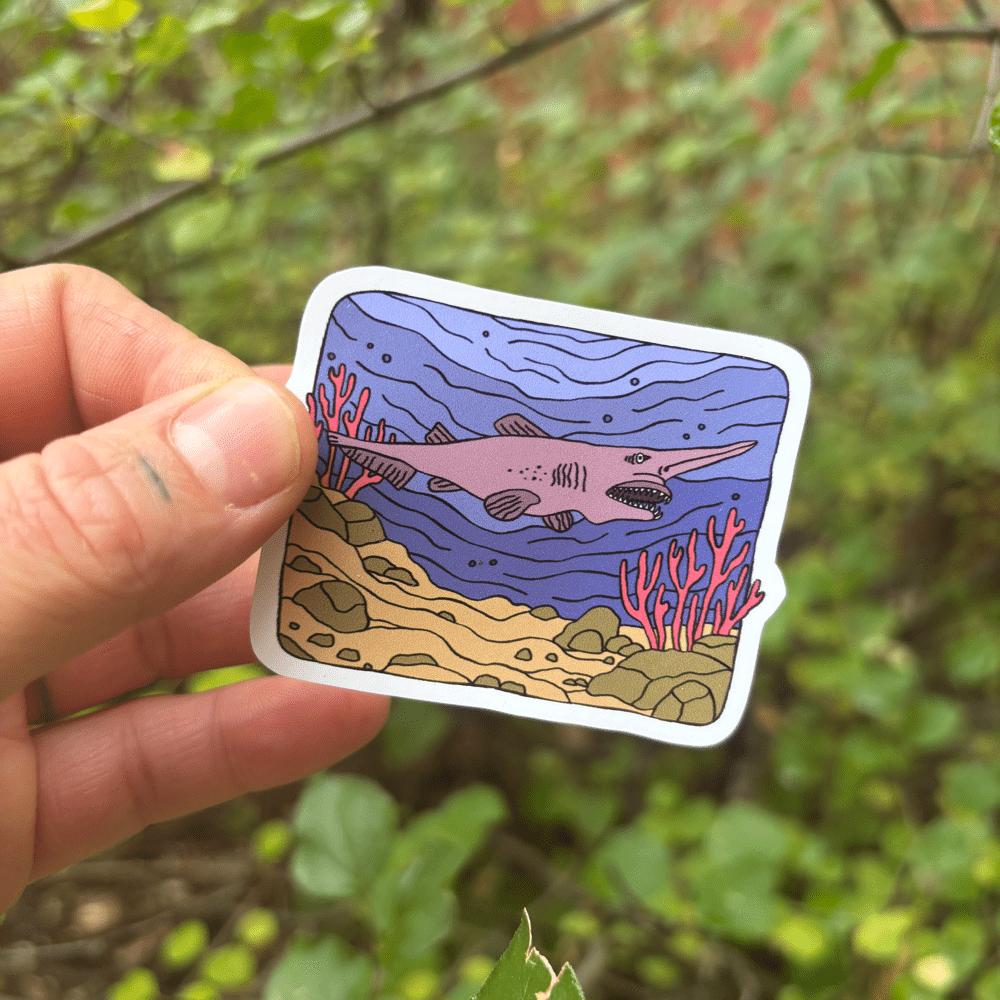 Hand holding a sticker of a goblin shark